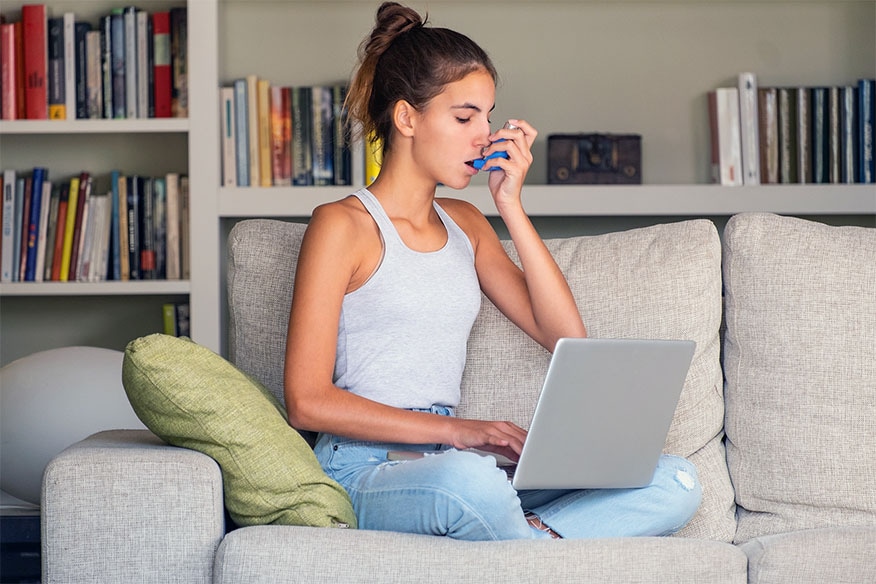 A person on a sofa with an inhaler